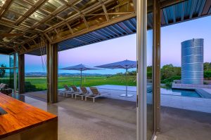 Open kitchen pavilion dissolving into the pool terrace at dusk, Healdsburg House
